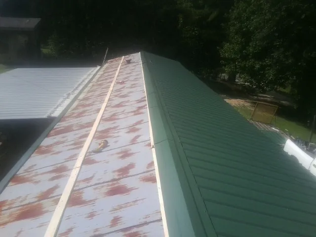 Old rusted panels beside newly installed green metal roofing — Wind Damage Roof Repair by Roofing Brothers in Grand Ridge