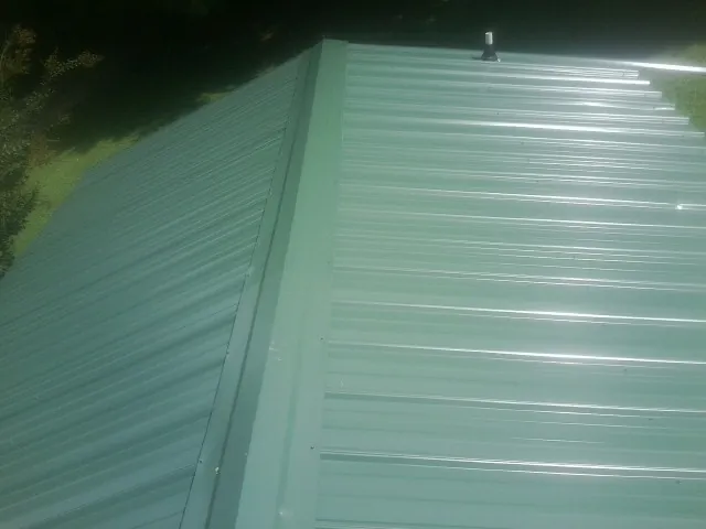 New green metal panels meeting at the ridge of a roof — Flat Roof Repair work by our crew in Grand Ridge