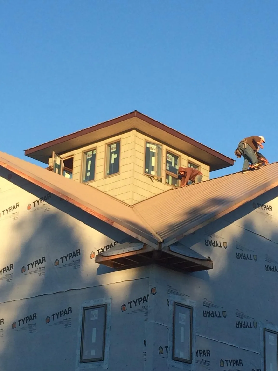 Roofers working around a rooftop cupola on a new metal roof at sunset — Roof Waterproofing in Grand Ridge by Roofing Brothers